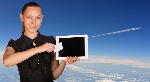 Beautiful businesswoman holding tablet PC and business card in front of screen. Blue sky with clowds as backdrop