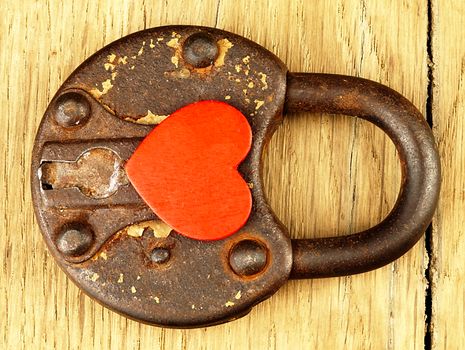 Rusty padlock and heart on a wooden background.