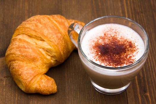 Cappuccino and croissant on wood