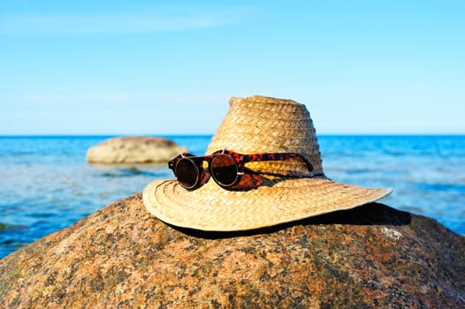 Straw hat with glasses on the seashore