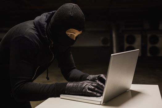 Robber at desk hacking a laptop 