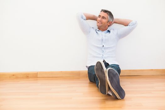 Smiling man sitting on the parquet relaxing 