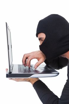 Focused burglar with balaclava typing on laptop