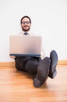 Businessman sitting on the floor using his laptop in the living room