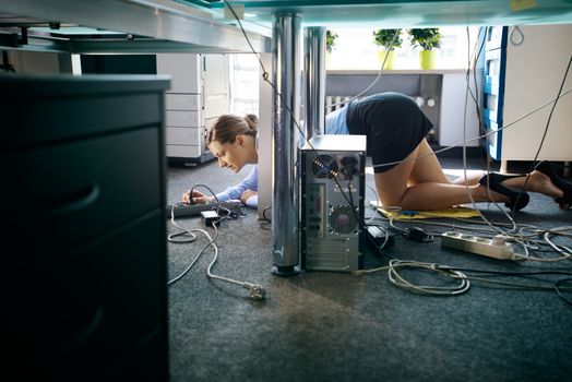 Young worker connecting cables and wires to computer in office
