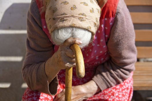 hands of an old woman with a cane