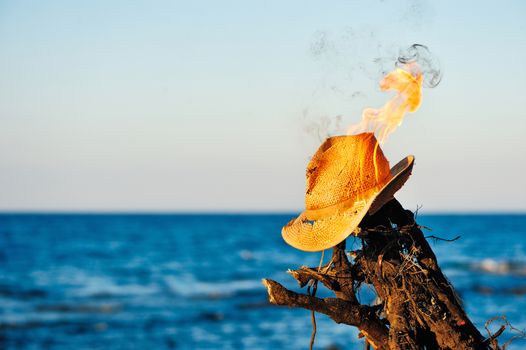 Burning wicker hat on the seashore