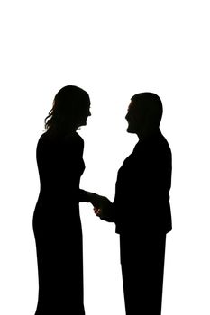 young loving couple holding hands in silhouette against a bright light gazing into each others eyes