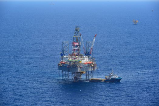 The offshore drilling oil rig and supply boat side view