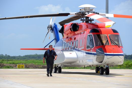 offshore helicopter pilot is walking and smiling beside of S92 h