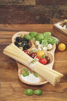Ingredients for Italian Spaghetti. Italian Pasta spaghetti with tomatoes, olives, mozzarella and Parmesan cheese and basil. Ingredients for cooking over rustic table.