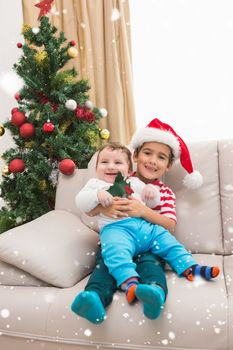 Composite image of cute boy and baby brother on couch at christmas