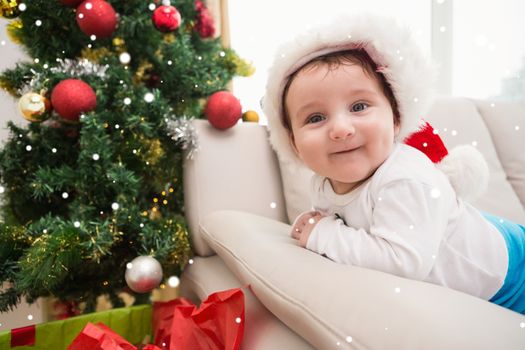 Composite image of cute baby boy on couch at christmas