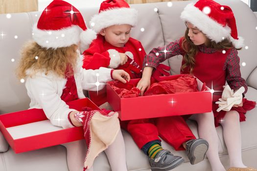 Composite image of festive little siblings opening a gift