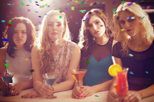 Composite image of attractive friends drinking cocktails together