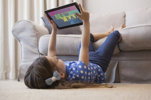 Composite image of little girl using digital tablet in the living room