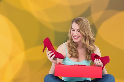 Composite image of blonde woman discovering shoes in a gift box