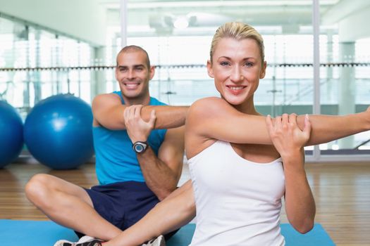 Portrait of happy young couple stretching hands in yoga class