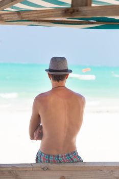 Hipster man with hat on tropical sandy beach.