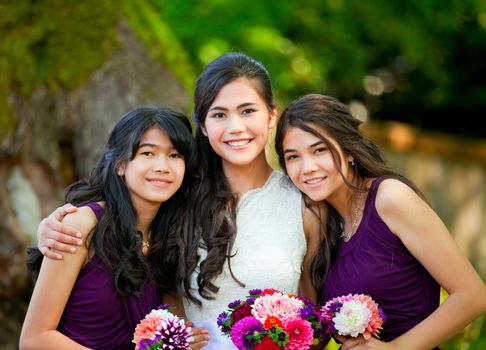 Bride with her two bridesmaid holding bouquet outdoors together
