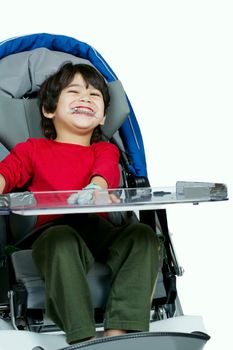 Three year old biracial disabled boy in medical stroller, happy 