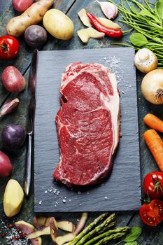 Food background with fresh vegetables and raw beef steak