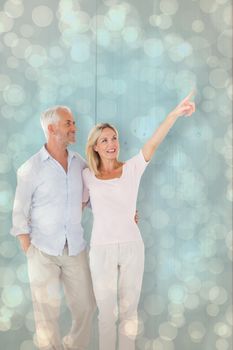 Smiling couple walking and pointing against light glowing dots design pattern