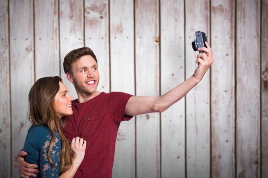 Couple taking selfie with digital camera against wooden planks