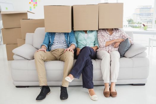 Colleagues sitting on couch covering with cardboard box 