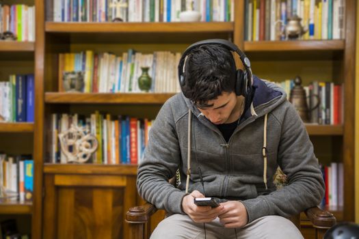 Attractive young man sitting listening to music on a set of stereo headphones
