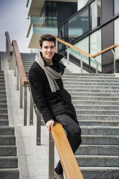 Trendy handsome young man in winter fashion standing on a long staircase