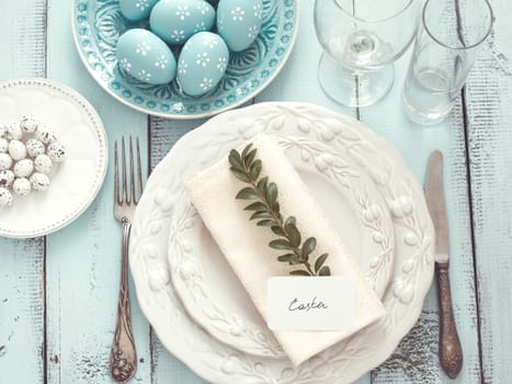 Easter table setting with holiday decor on mint wooden background, top view point