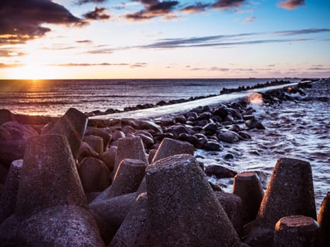 Sunset on the coast of the Riga Gulf at dawn with rocks in foreground