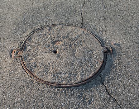 Manhole with the cover paved with asphalt