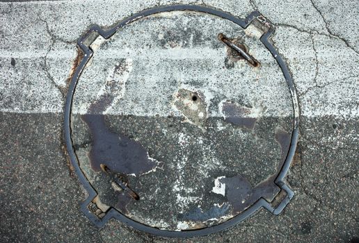 Manhole with metal cover with zebra crossing marking line on it