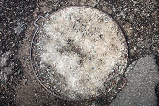 Manhole with the metal cover surface paved with asphalt