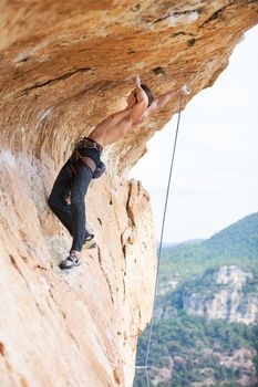 Young man clipping rope while clinging to cliff