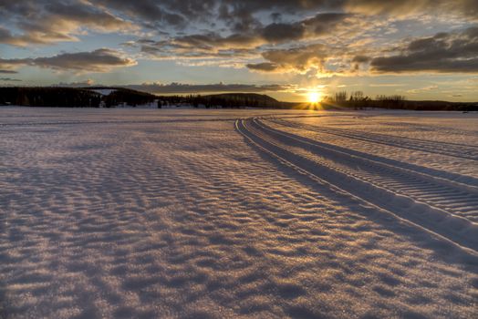 Snowmobile Tracks Heading into the Sunset on lake