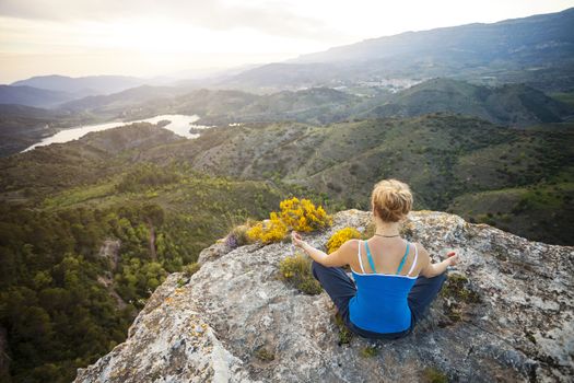 Woman sitting on a rock and enjoying valley view