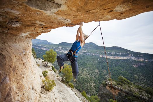 Woman climber struggling to make next movement up