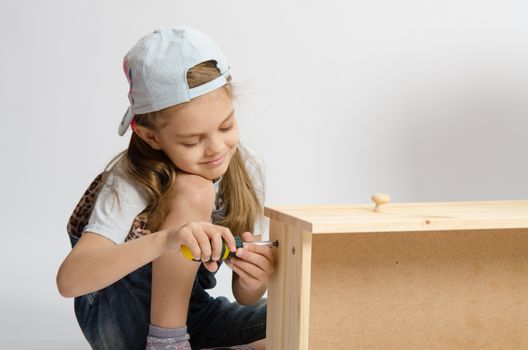 Little girl in overalls collector of furniture screws screwdriver screw