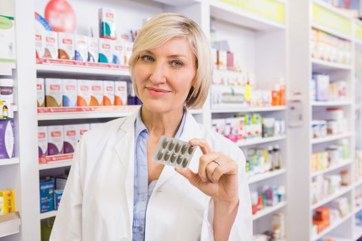 Smiling pharmacist showing blister 