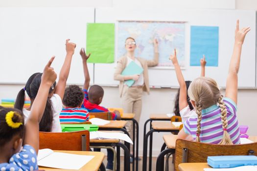 Pupils raising hand during geography lesson in classroom