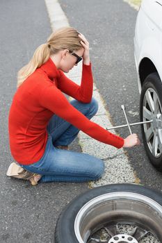 Annoyed woman trying to replace tire