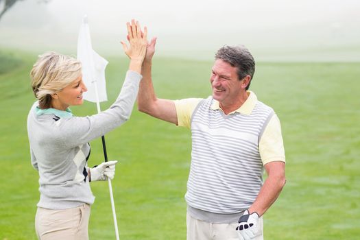 Golfing couple high fiving 