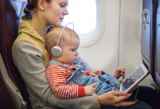 Mother and son using tablet on board of airplane