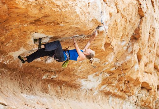 Rock climber struggling to make next movement up