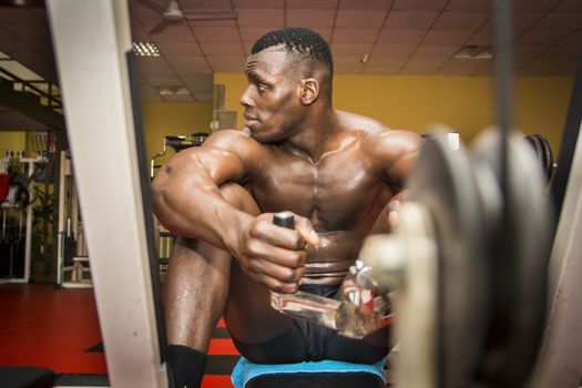 Hunky muscular black bodybuilder working out in gym