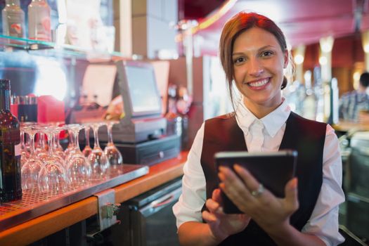 Focused barmaid using touchscreen till 