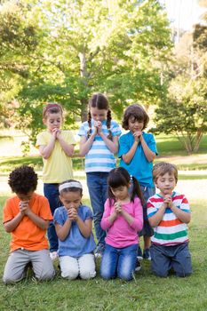 Children saying their prayers in park